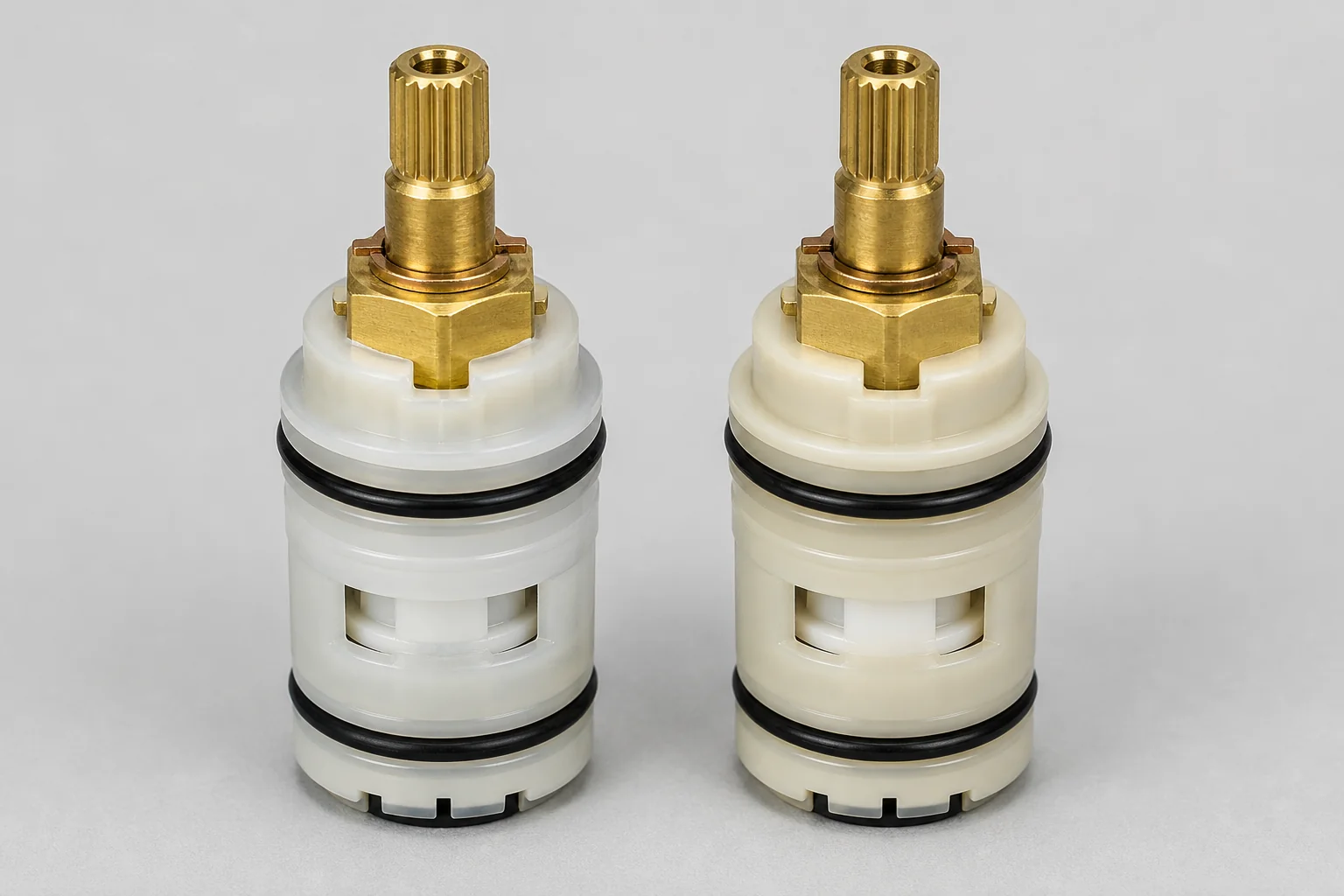 A genuine OEM faucet cartridge next to a similar-looking aftermarket replacement cartridge, side by side