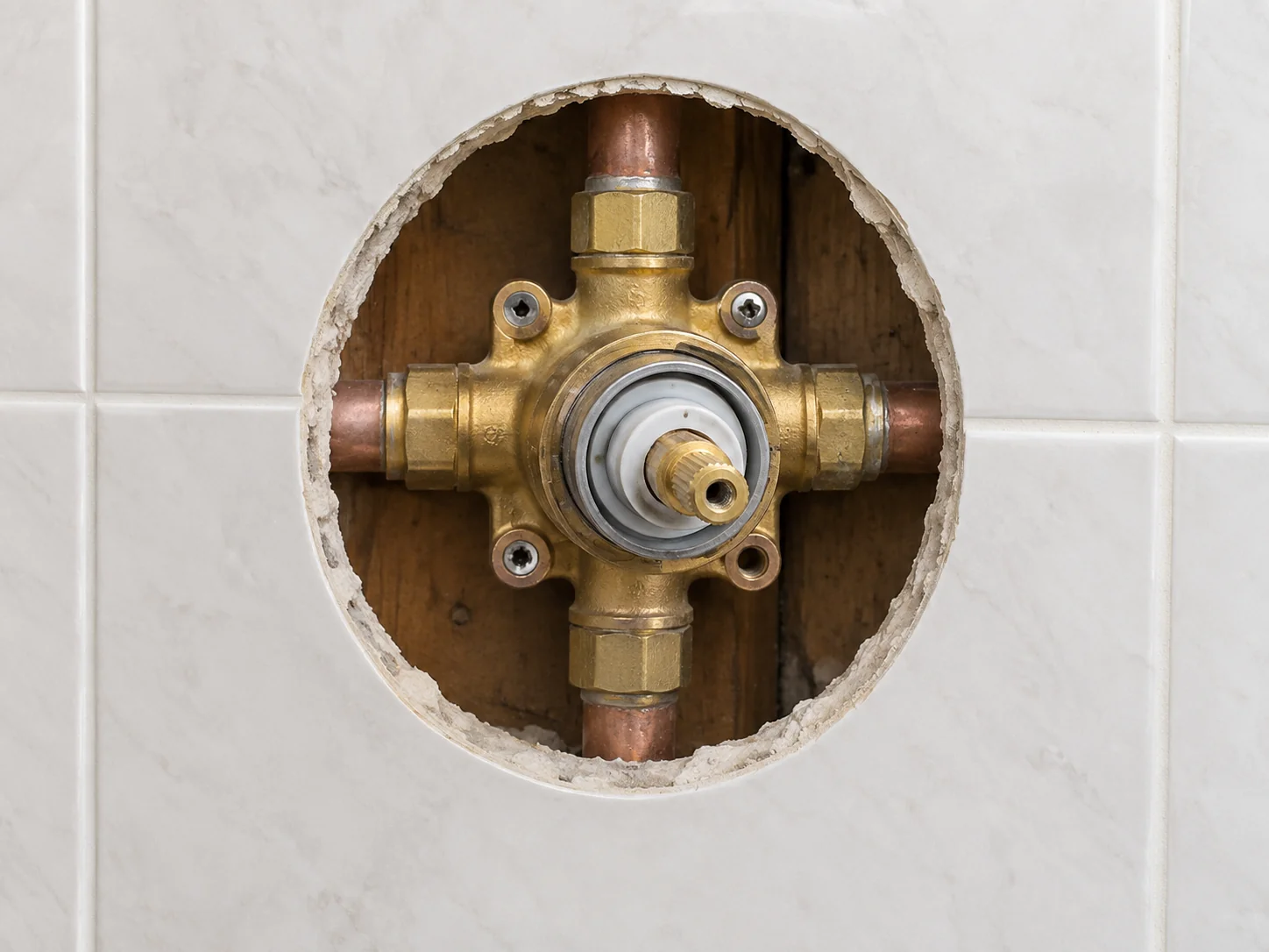 A shower valve with the escutcheon plate removed, showing the exposed valve body and cartridge