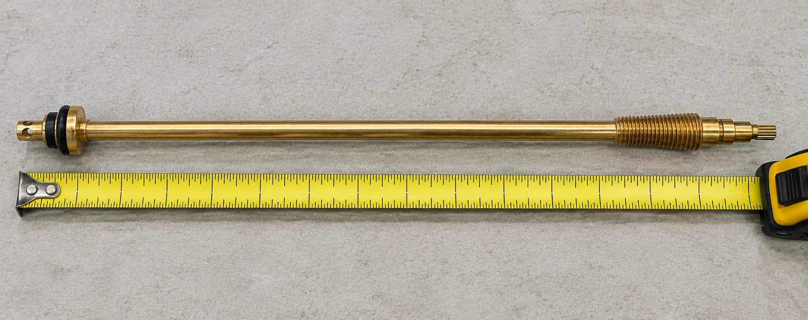 A long frost-free faucet stem laid beside a tape measure, measured from one brass tip to the other